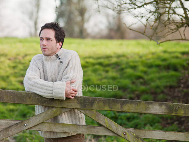 Homem inclinado no portão de madeira ao ar livre — Fotografia de Stock