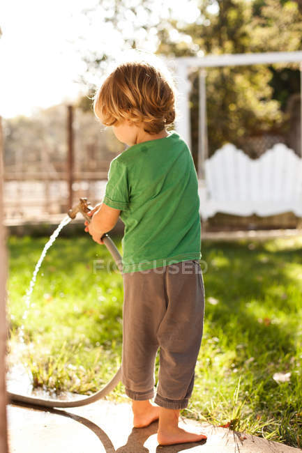 Niño usando manguera en el patio trasero - foto de stock