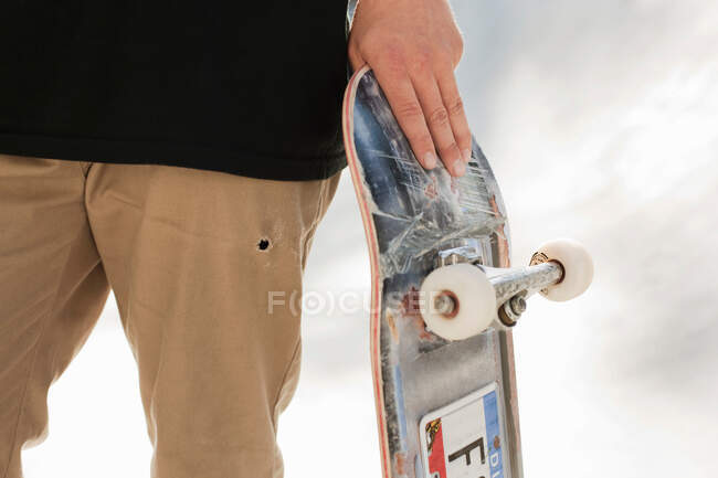Adolescente sosteniendo monopatín en las manos - foto de stock
