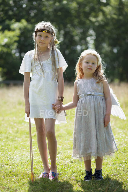 Two girls in costumes holding hands — Stock Photo