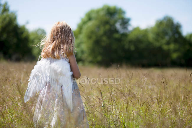 Ragazza che indossa ali d'angelo in campo — Foto stock