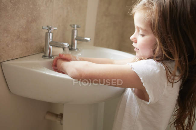 Chica lavándose las manos en el baño - foto de stock