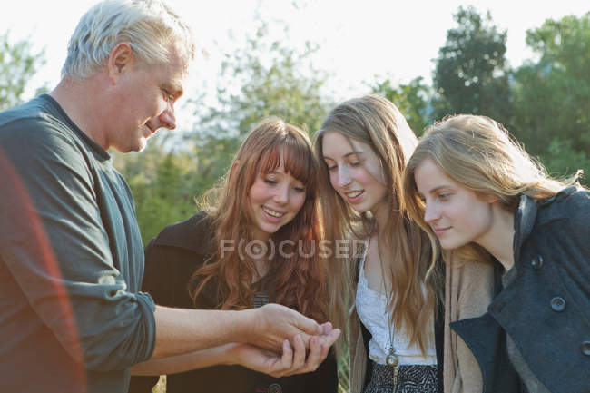 Man offering something to teenage girls — Stock Photo