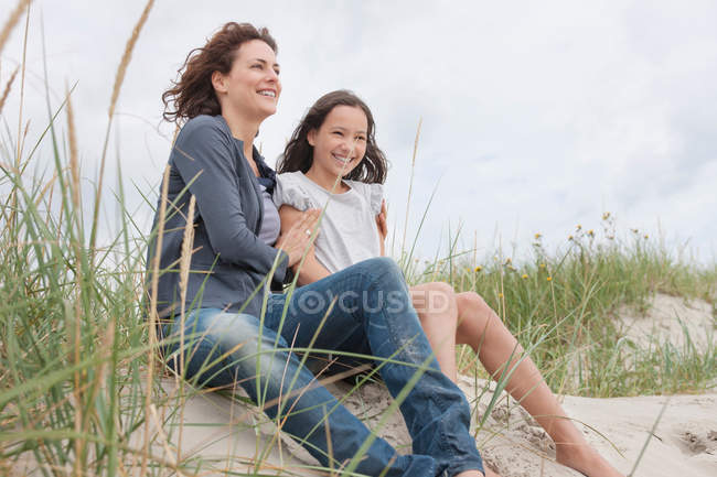 Mãe e filha sentadas na praia — Fotografia de Stock