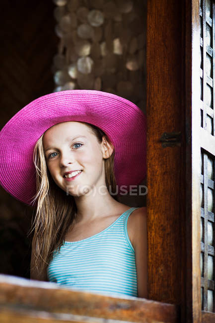 Girl wearing straw hat at window — Stock Photo