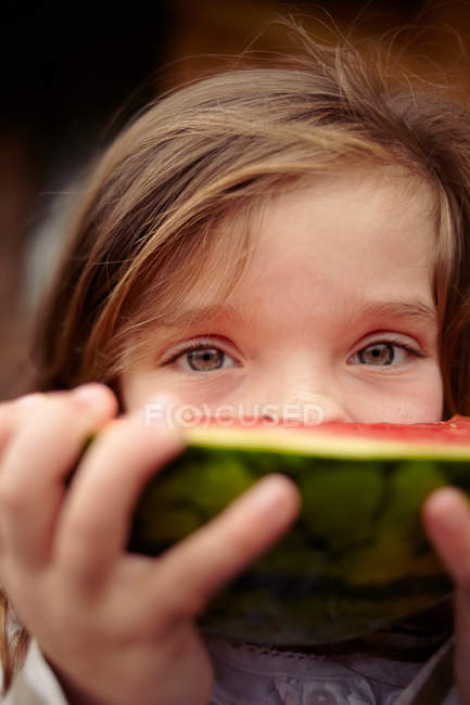 Fille manger pastèque et regarder la caméra — Photo de stock