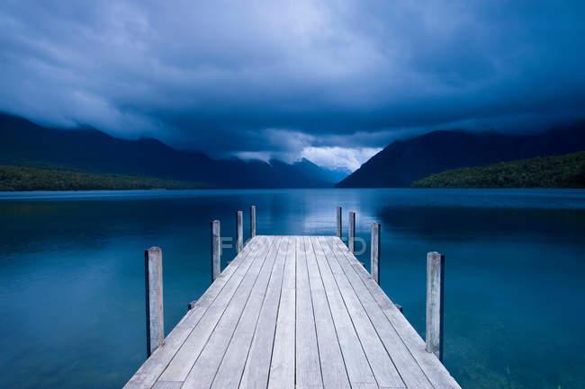 Wooden pier stretching into still lake — Stock Photo