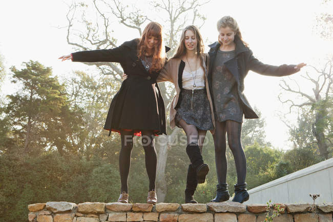 Girls walking on stone wall — Stock Photo