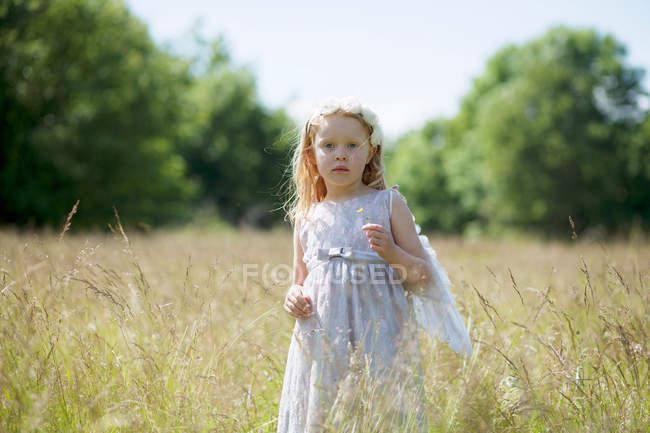 Girl wearing angel wings in field — Stock Photo