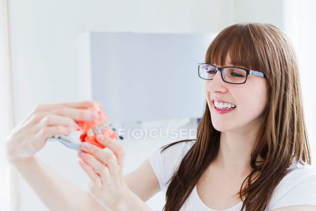 Усміхнена жінка тримає модель зубів — стокове фото