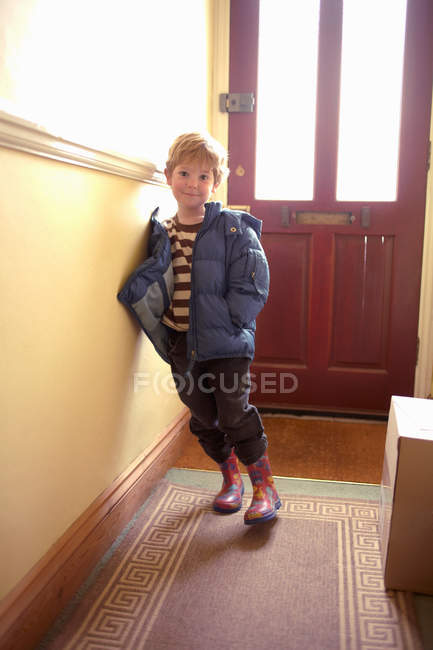 Niño con parka y botas en el interior - foto de stock