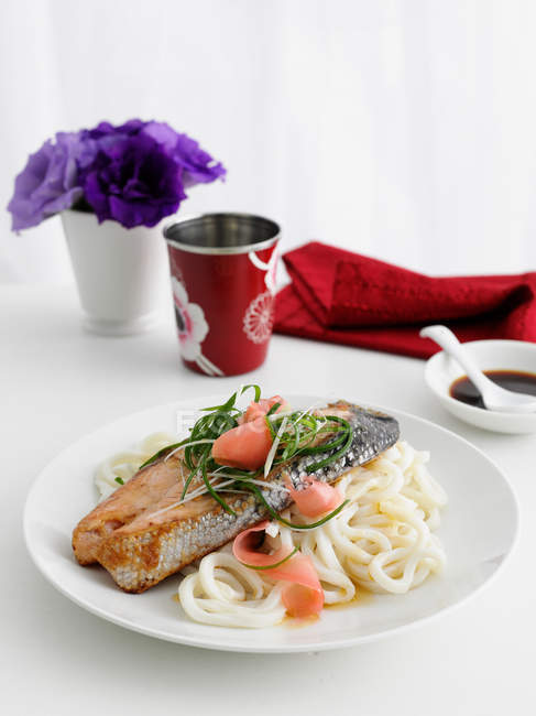 Plate of fish and pasta on table — Stock Photo