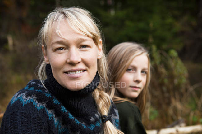 Улыбающиеся мать и дочь в лесу — стоковое фото