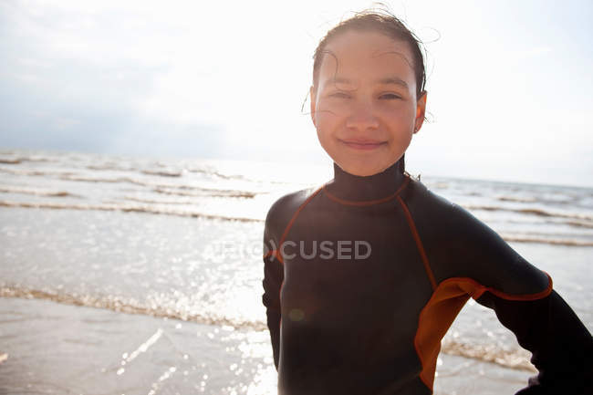 Улыбающаяся девушка в гидрокостюме на пляже — стоковое фото