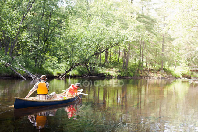 Father and son paddling canoe — Stock Photo