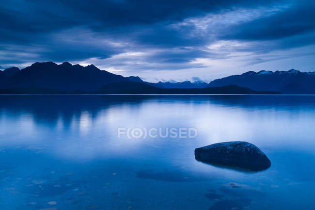 Montanhas refletidas em lago imóvel — Fotografia de Stock