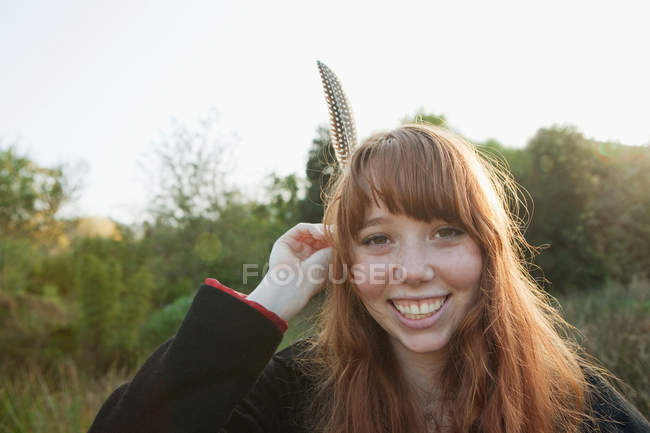 Teenage girl holding feather in hair — Stock Photo