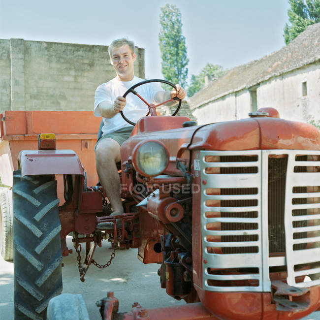 Людина сидить на антикварному тракторі — стокове фото