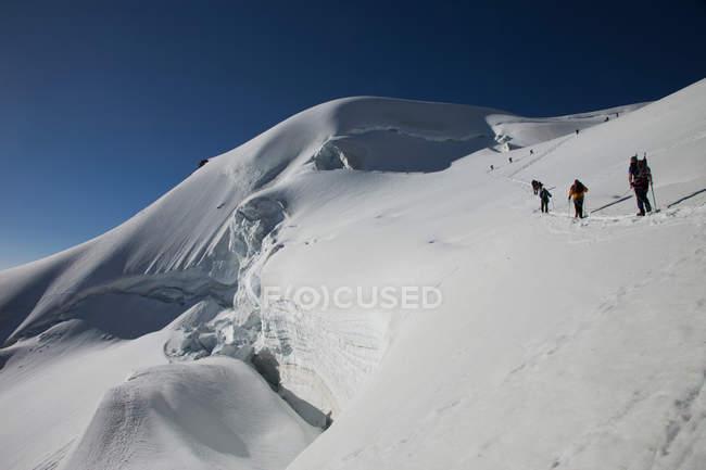 Mochileros caminando sobre montañas nevadas - foto de stock