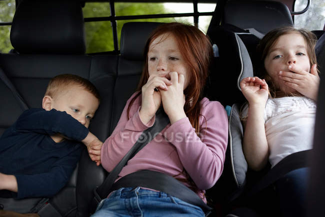Bostezar a los niños en el asiento trasero del coche - foto de stock