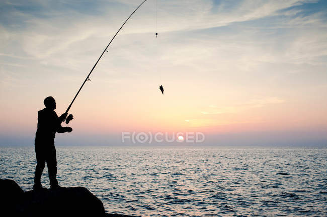 Людина риболовля на заході сонця — стокове фото