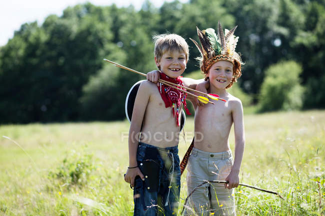 Boys in costumes hugging in field — Stock Photo