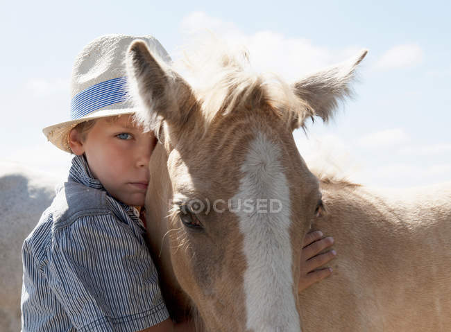 Menino de estimação cavalo ao ar livre — Fotografia de Stock