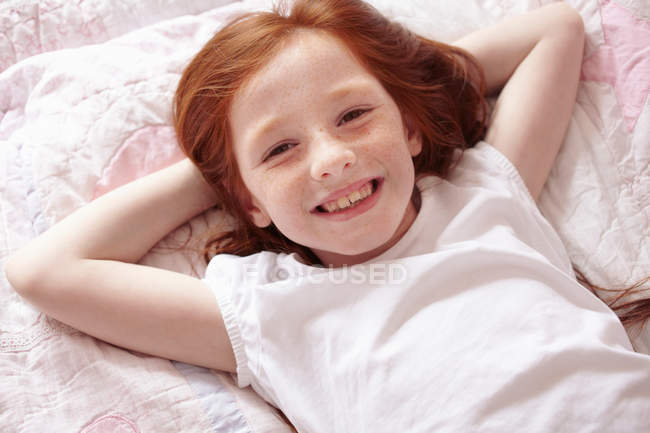 Lächelndes Mädchen auf dem Bett liegend — Stockfoto