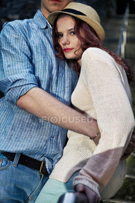 Mujer abrazando novio y mirando a la cámara - foto de stock