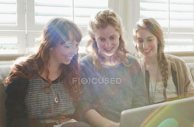 Girls using laptop on couch — Stock Photo