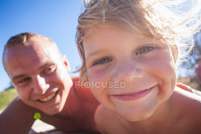 Chico sonriendo a cámara con padre - foto de stock