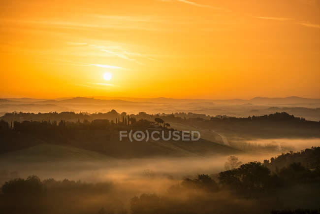 Nascer do sol sobre a paisagem rural nebulosa — Fotografia de Stock