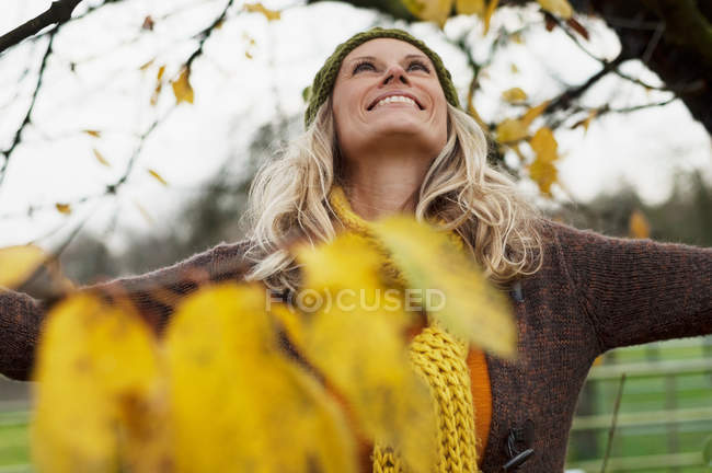 Femme souriante regardant vers le haut de l'arbre — Photo de stock