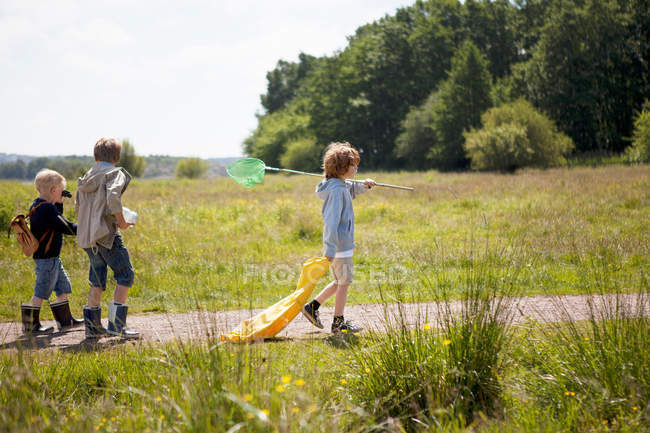 Tres niños caminando por el camino de tierra - foto de stock