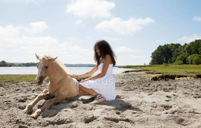 Дівчина пестить коня на піщаному пляжі — стокове фото