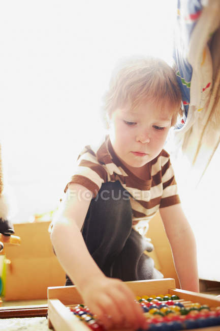 Мальчик играет с абакусом в помещении — стоковое фото