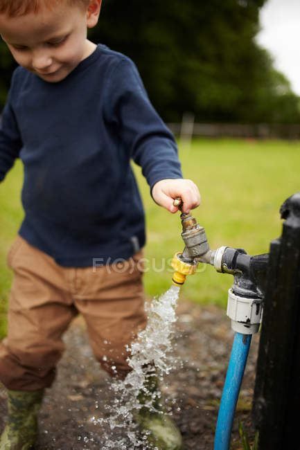 Boy opening bibcock outdoors — Stock Photo