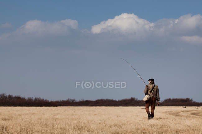 Hombre llevando caña de pescar - foto de stock