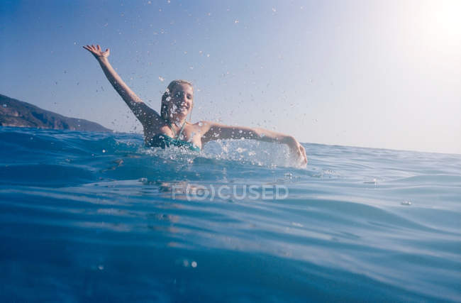 Mulher espirrando no mar azul — Fotografia de Stock
