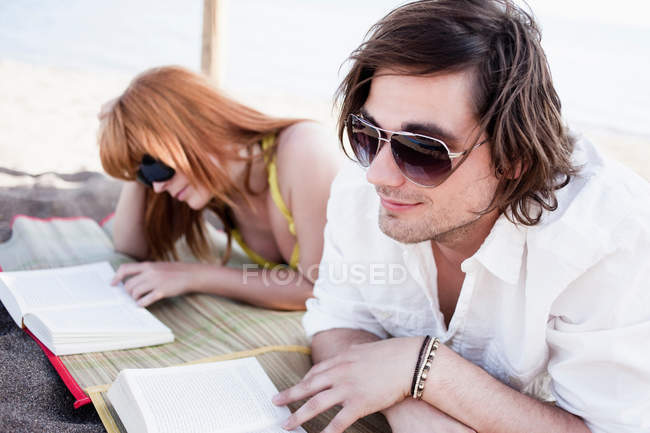 Pareja leyendo en la playa - foto de stock