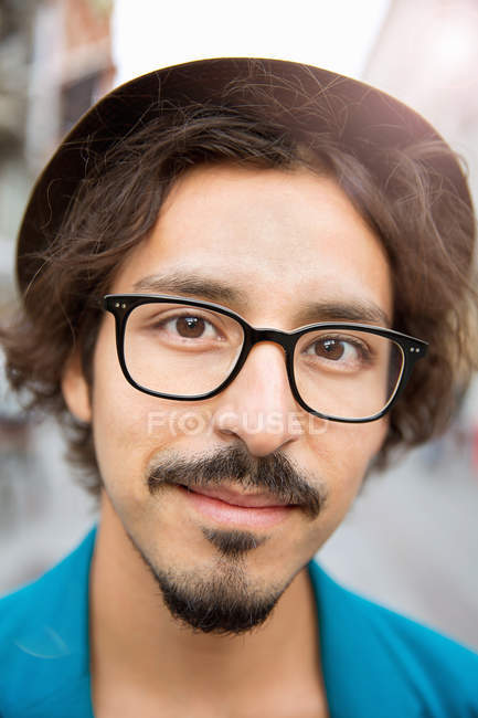 Retrato de un joven con gafas y sombrero mirando a la cámara - foto de stock