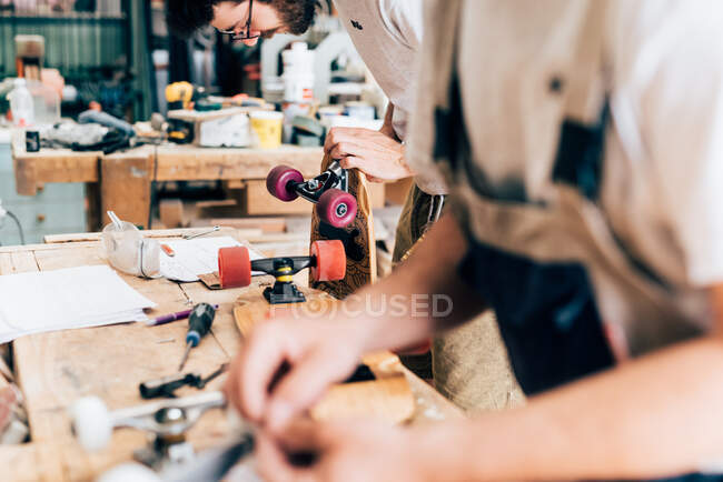 Young men in carpentry workshop looking down making skateboards — Stock Photo