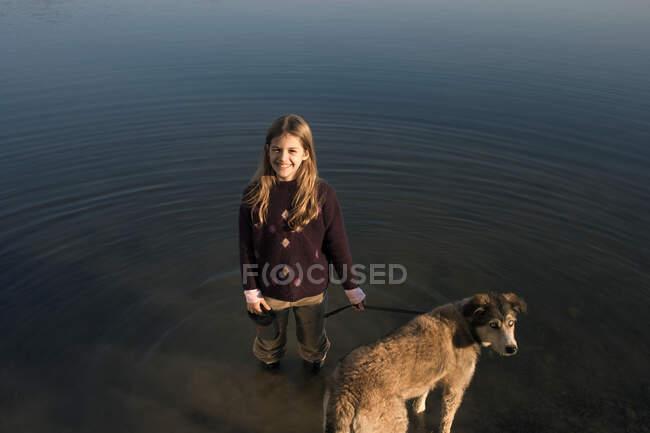 Дівчина стоїть в річці тримає собаку — стокове фото