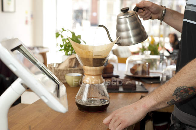 Hände des Cafékellners schütten kochendes Wasser in Filterkaffeekanne — Stockfoto
