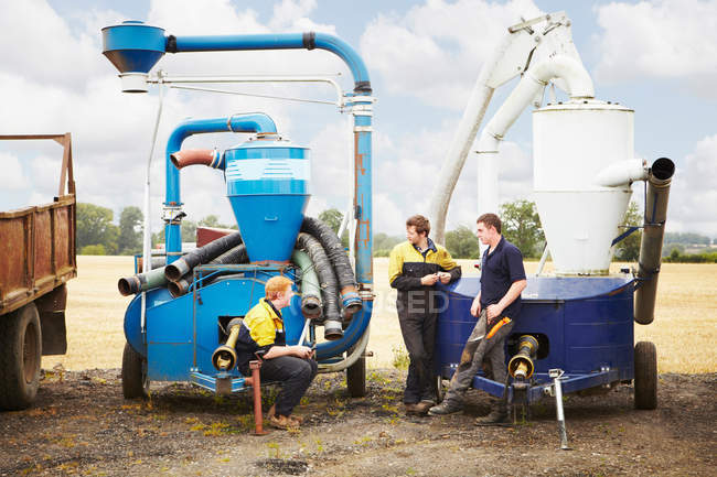 Farmers talking by machinery in field — Stock Photo