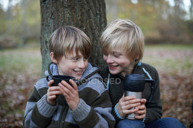 Jungen trinken heiße Getränke im herbstlichen Wald — Stockfoto