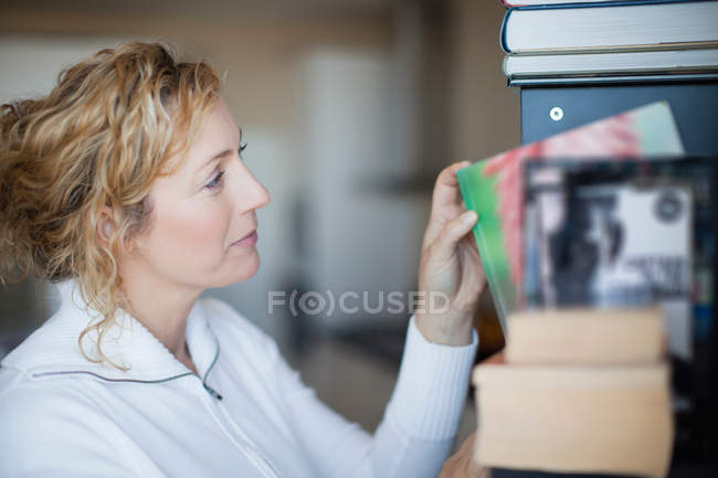 Женщина организует книжную полку, сфокусируйтесь на переднем плане — стоковое фото
