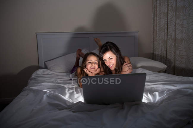 Madre e figlia utilizzando il computer portatile a letto — Foto stock