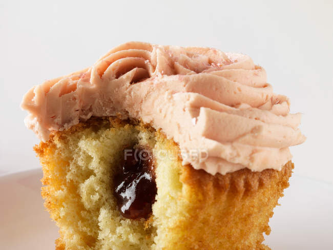 Filled bitten cupcake on white — Stock Photo