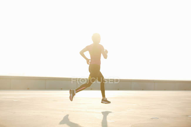 Homem correndo no telhado à luz do sol — Fotografia de Stock